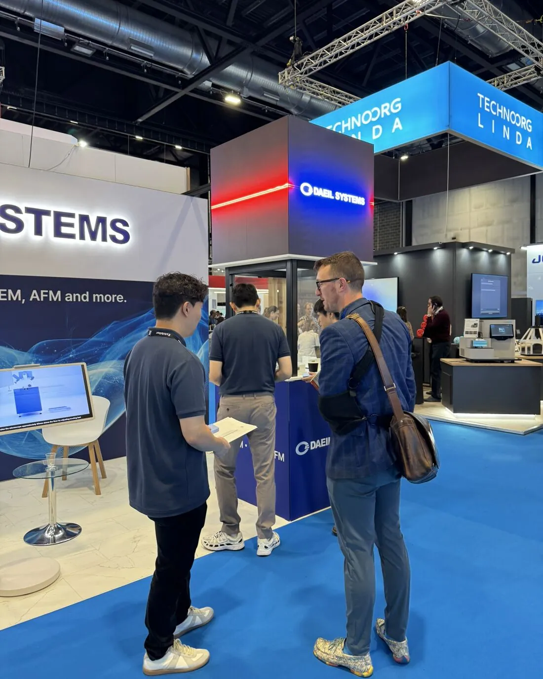 A DAEIL SYSTEMS team member talks with visitors at the front of Stand 345